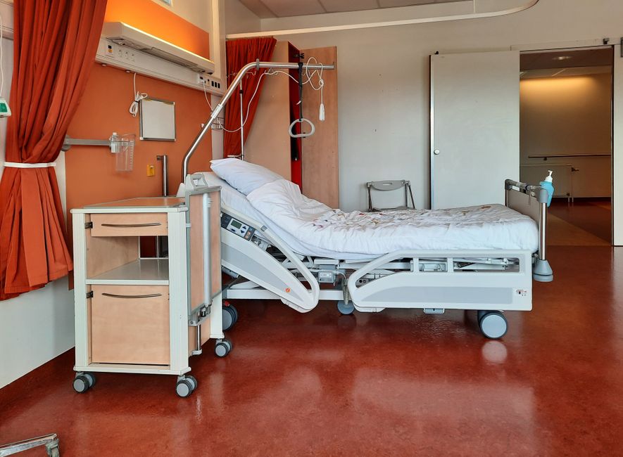 A clean and modern hospital room equipped with an adjustable bed and medical equipment.