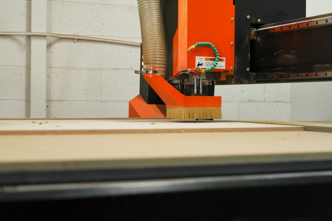 An orange cnc machine cutting wood with a brush attachment.