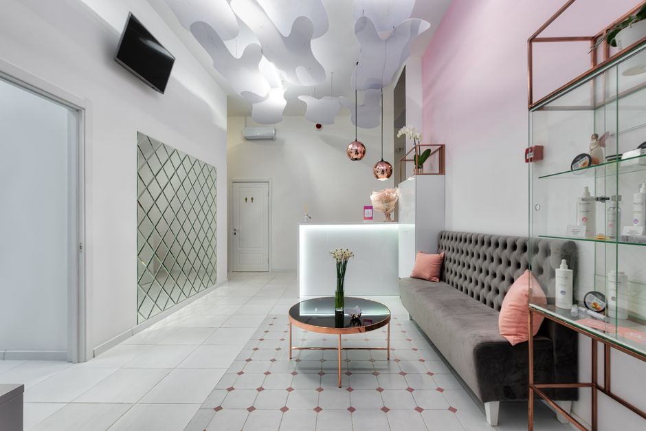 Interior of contemporary reception hall with sofa and glass table with TV set hanging on wall in beauty salon