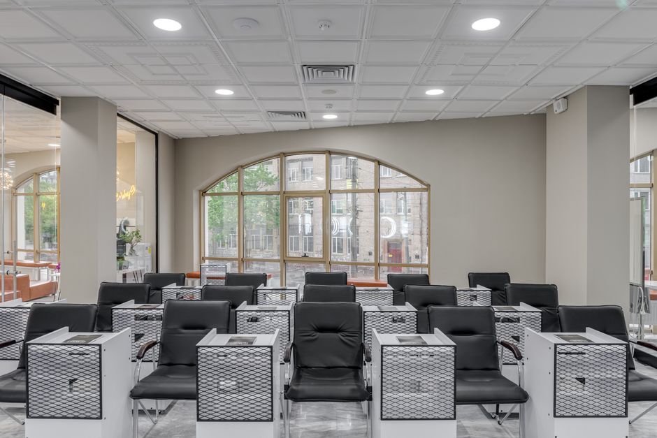 Spacious salon with black leather chairs and large glass windows for natural light.