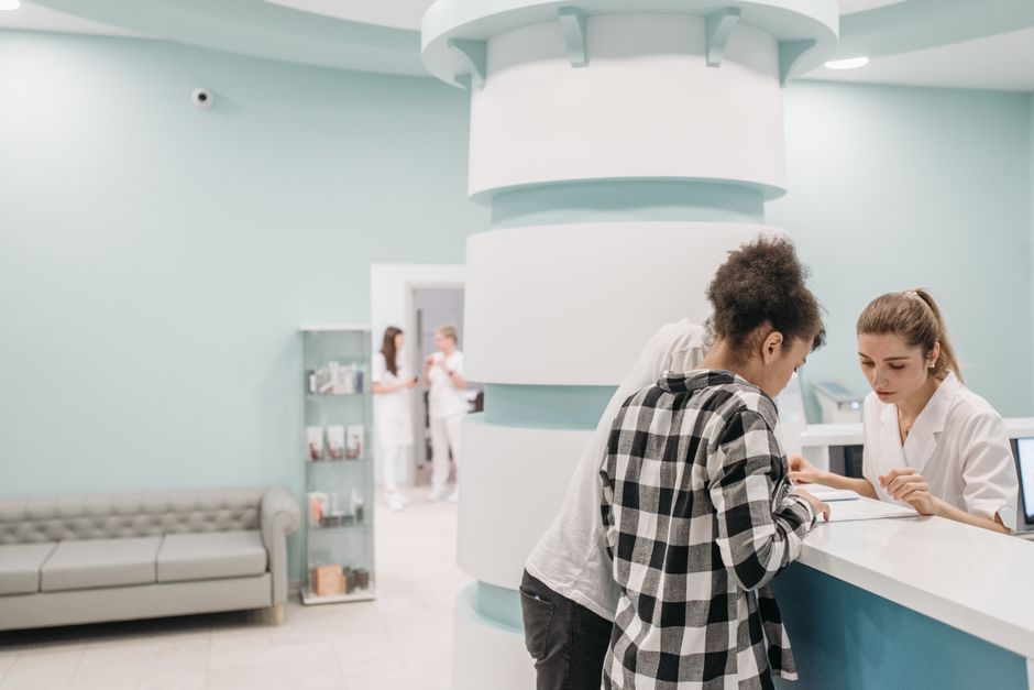 Healthcare professionals assisting at a modern clinic reception desk.